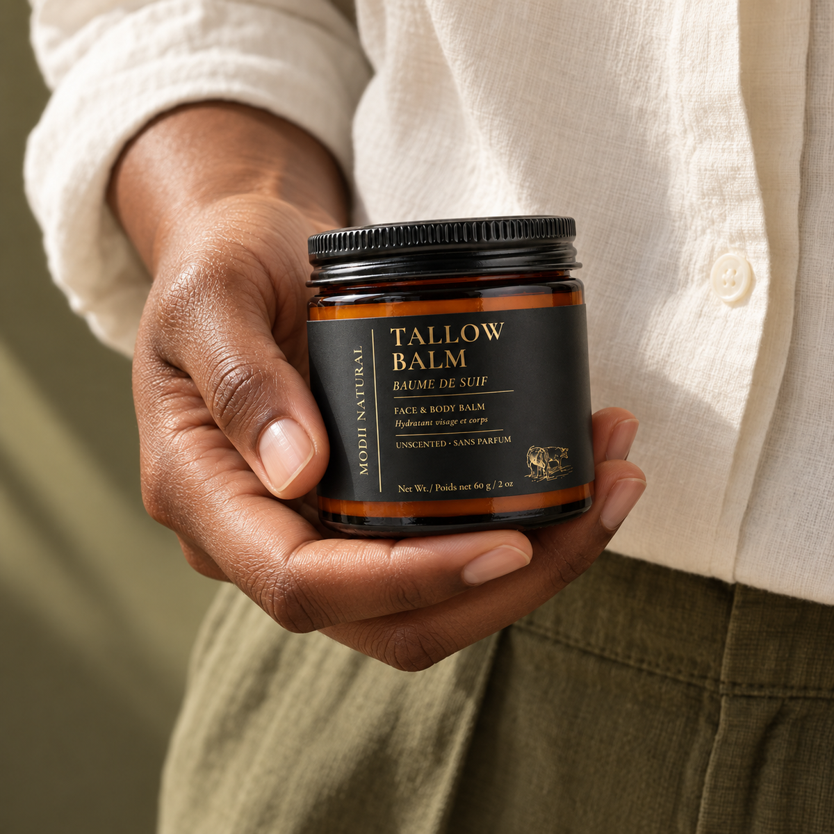 MODII Natural Tallow Balm — product shown in adult hands for scale
